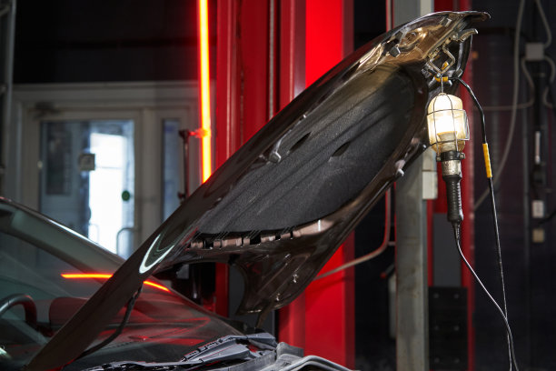 便携式灯挂在汽车服务的敞开式引擎盖上，发出明亮的光图片下载