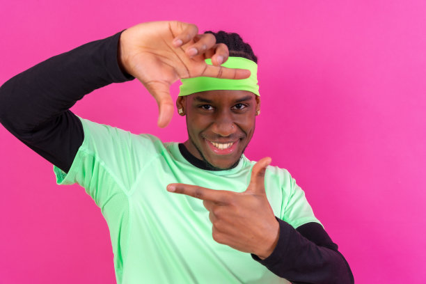 黑色民族男子在绿色的衣服在粉红色的背景，概念肖像，手势微笑图片下载