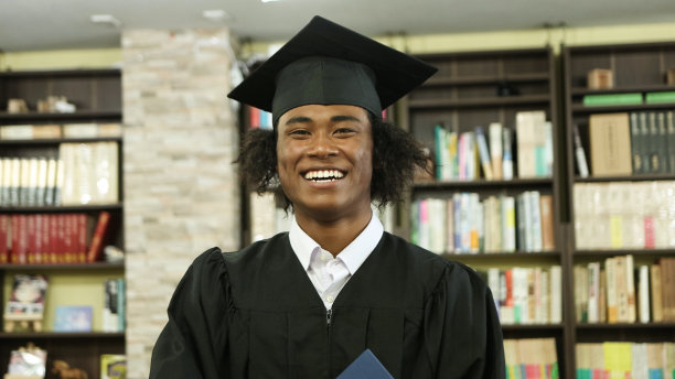 年轻的黑人毕业生在图书馆微笑的肖像图片下载