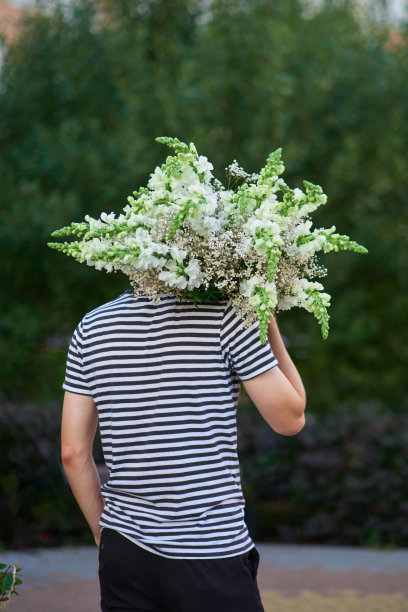 男子拿着一束白色的花在绿色的背景，夏天，春天的概念图片下载