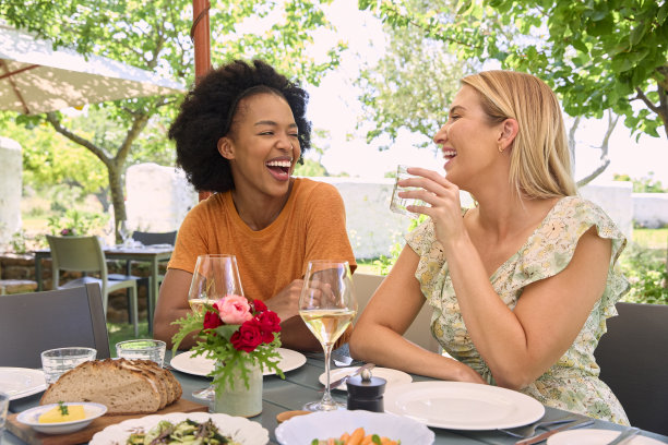 两位女性朋友在参观葡萄园餐厅时享受户外用餐和葡萄酒图片下载