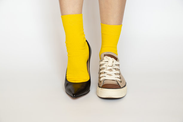 不同的鞋子穿在女孩的腿上，高跟鞋和运动鞋黄袜子在白色的背景图片下载