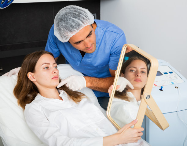 女顾客看着镜子，美容师检查她的面部皮肤图片下载