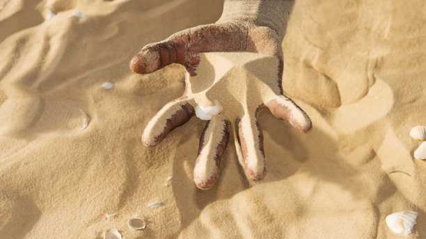 气候变化。手里拿着沙子的人。荒漠化和干旱的象征性表现。照片图片下载