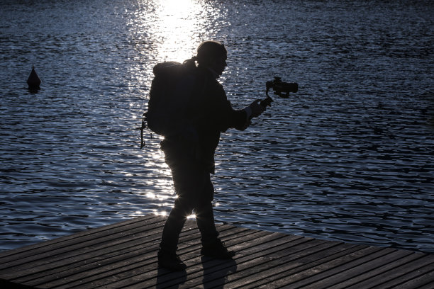 摄影师拍摄与云台在水日落图片下载