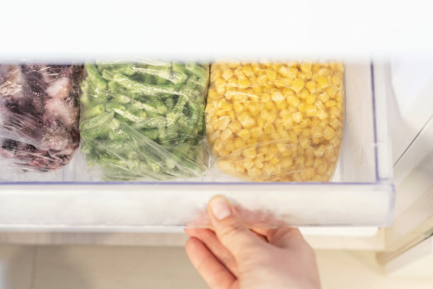 女性的手打开冰箱里冷冻食品的架子。图片下载