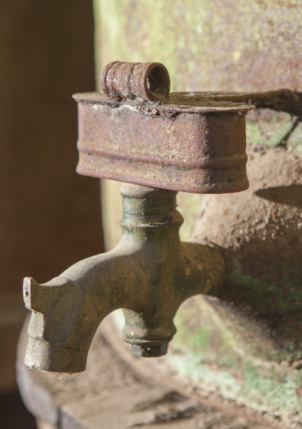 旧橄榄油桶上生锈的水龙头图片下载