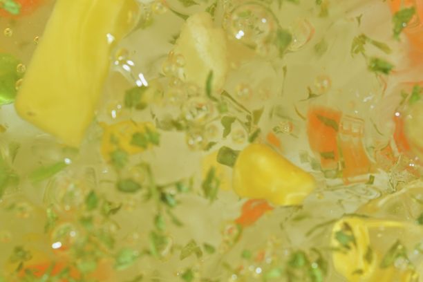 近景的蔬菜与胡萝卜，豌豆，花椰菜，玉米，切碎的土豆和欧芹在水的背景。蔬菜煮汤的口感。平面设计，俯视图。水平微距图像。散焦图片下载