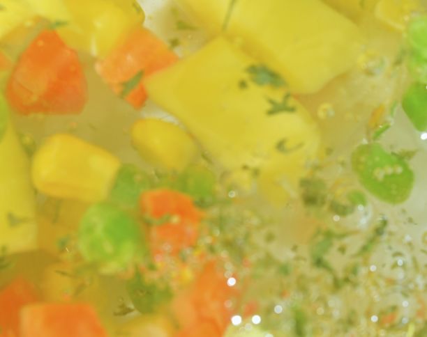 沸水加新鲜蔬菜，特写。近景的蔬菜汤与胡萝卜，豌豆，花椰菜，玉米，切碎的土豆和欧芹在水的背景。水煮蔬菜的质感，玻璃墙上有大气泡。扁平化设计图片下载