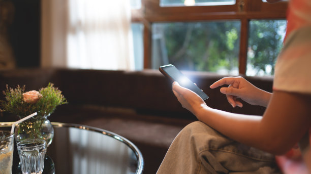 近距离的女人手拿智能手机在舒适的咖啡馆，网上购物。图片下载