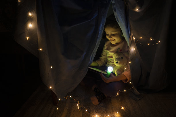 小女孩在客厅的自制帐篷下使用平板电脑图片下载