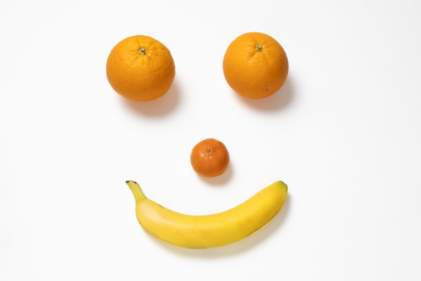 一个笑脸由两个橘子，一个橘子和一个香蕉，在白色的背景上图片下载