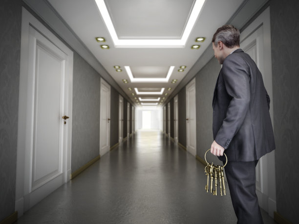一个看不见脸的CGI人物拿着一串金钥匙站在走廊入口，通往一排关着门的走廊。选择和决策概念图片下载
