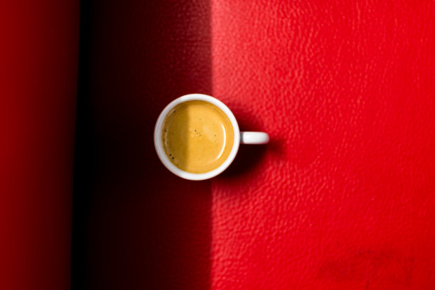 红色皮沙发上放着一个浓缩咖啡杯图片下载