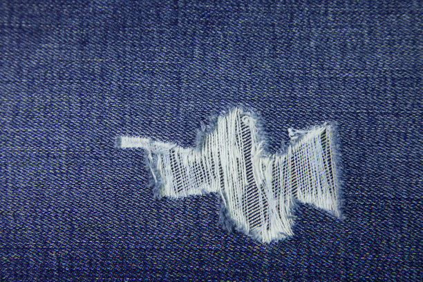 撕裂牛仔裤面料背景纹理。破牛仔裤面料布纺织材料。图片下载