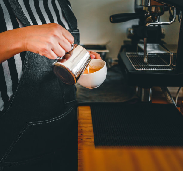 专业的咖啡师在咖啡店制作，将蒸好的牛奶倒进咖啡杯，制作拿铁菜单图片下载