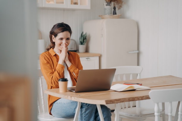 惊喜兴奋的年轻女子坐在笔记本电脑前进行视频通话。距离工作。图片下载
