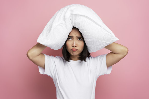 生气的女人在早上用枕头捂住耳朵，因为噪音太大图片下载