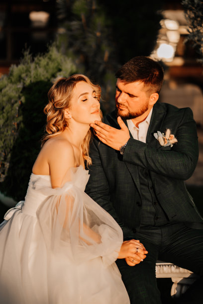 温柔的新娘和新郎坐在公园的长椅上。图片下载