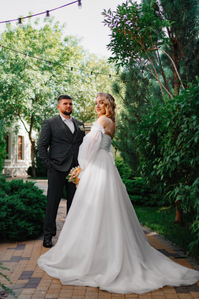 美丽而时尚的新娘和新郎在公园的小路上。图片下载