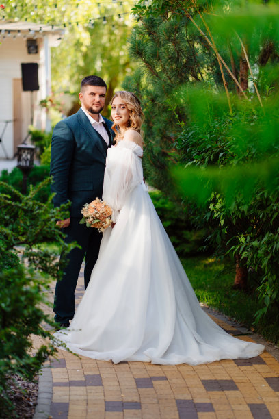 美丽而时尚的新娘和新郎在公园的小路上。图片下载