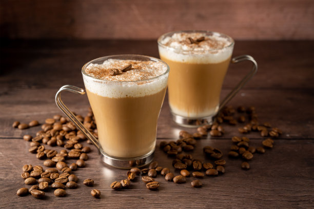 两杯咖啡热饮，牛奶泡沫装在玻璃杯里，背景是木制的图片下载