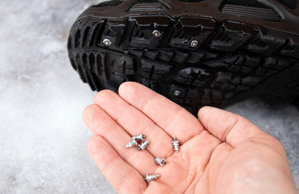 人的手显示自螺丝螺柱附在冬季靴子的鞋底。冬季防滑概念。在冰冷的街道上。靴子的轮胎钉。图片下载