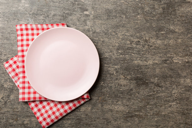 顶部视图上的彩色背景空圆形粉红盘子桌布上的食物。在餐巾纸上空出盘子，为你的设计留出空间图片下载