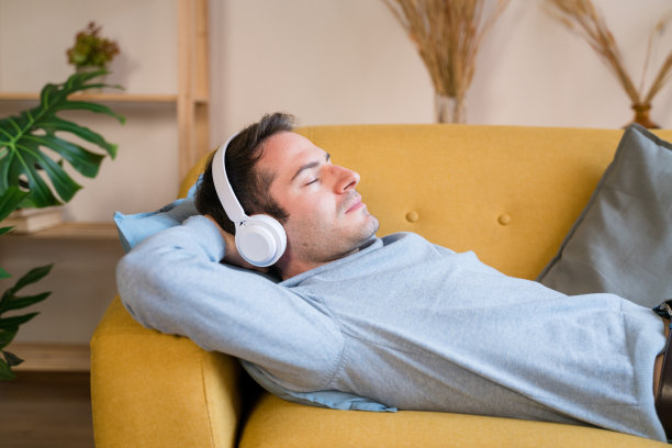 微笑的男人在沙发上听音乐图片下载