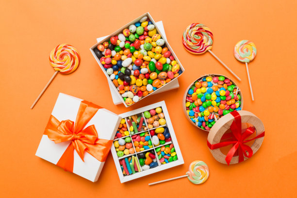 一套不同的糖果在一个纸盒与缎带的彩色背景。节日的概念图片下载
