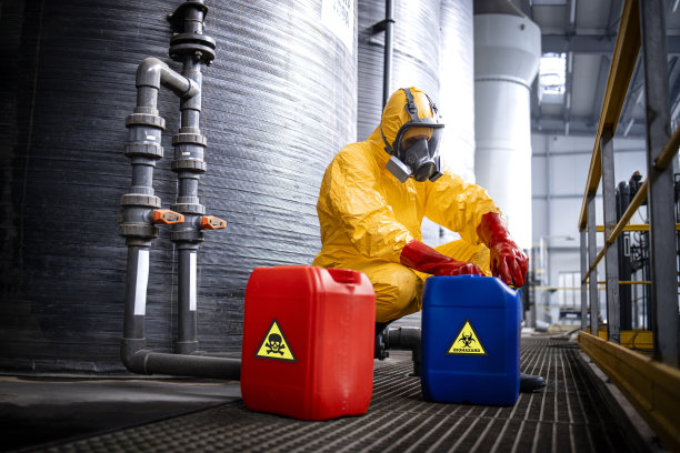 化学工业用于制酸。工厂工人穿着防护服，戴着防毒面具，小心地处理危险物品。图片下载