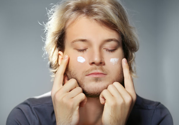 年轻男子用面膜照顾他的眼部皱纹。涂抹面霜图片下载