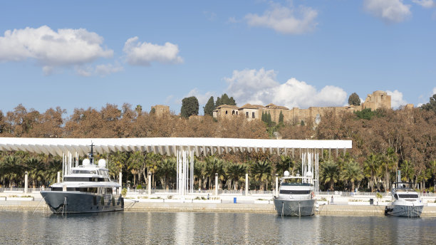 从一号码头看马拉加的阿尔卡扎巴，有游艇，蓝天。图片下载