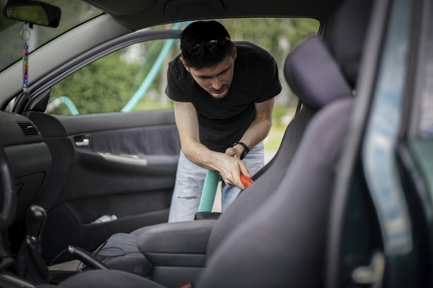 一名白人男子在加油站用吸尘器清扫汽车。图片下载