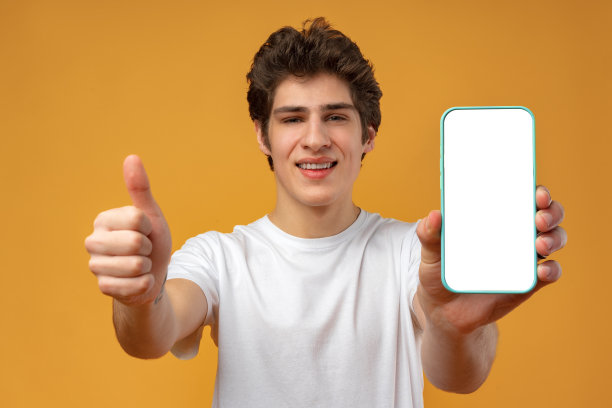 微笑的年轻人展示手机空白白屏幕的模型到相机。图片下载