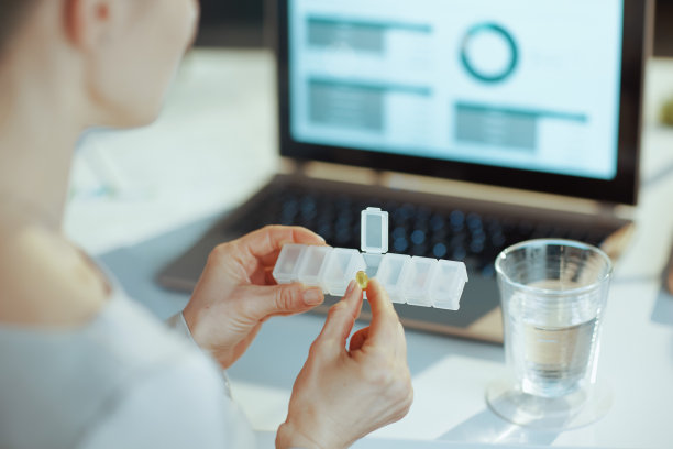 从后面看，现代女性拿着笔记本电脑和药片图片下载