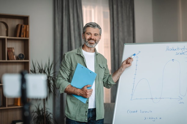 满脸胡须的快乐的欧洲男老师与学生开会，指着黑板图片下载