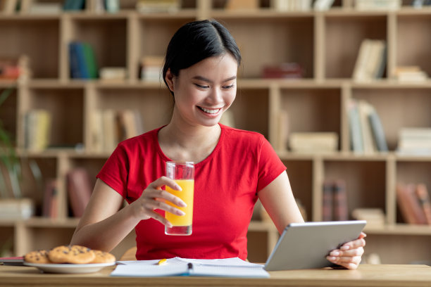 快乐的年轻亚洲女士在平板电脑上看视频课程，上网，喝果汁，吃早餐图片下载