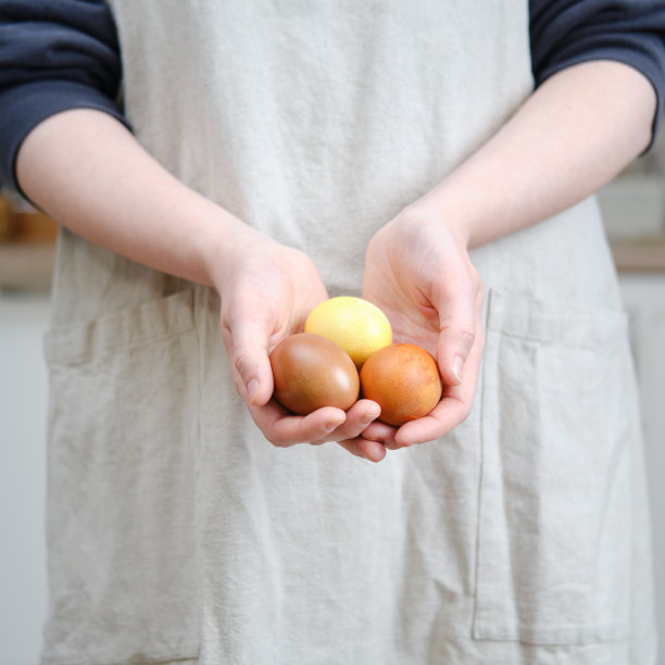 女人手里拿着彩绘的复活节彩蛋，家庭厨房背景图片下载