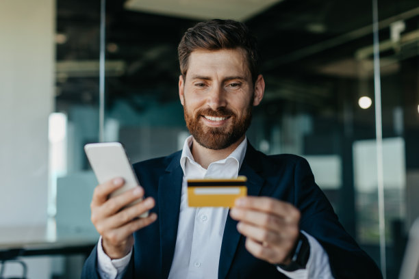 网上银行的概念。快乐的白人总经理坐在办公室里用智能手机在线支付图片下载