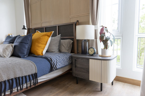 床上有黄色和绿色的枕头，床头柜上有白色的现代台灯。图片下载