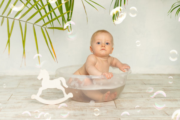 婴儿在白色背景上有泡沫和肥皂泡的盆里洗澡图片下载
