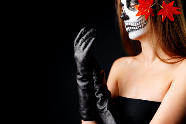 特写肖像创意万圣节化妆糖骷髅风格画在美丽的金发女人脸上的白色黑色油漆。深色的工作室背景。性感女孩看着相机。专业的人体艺术。图片下载