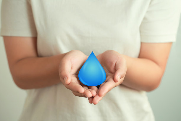 女人手里捧着一滴水，清洁可再生能源。世界水日概念。节约用水与世界环保理念。节约用水，拯救生命。图片下载