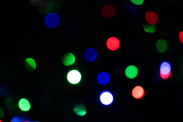 波光粼粼，绿的、红的、蓝的彩灯模糊地映在街上。街道上不集中的闪闪发光的灯光图片下载