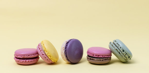 黄色背景上有五个彩色的蛋白杏仁饼。图片下载