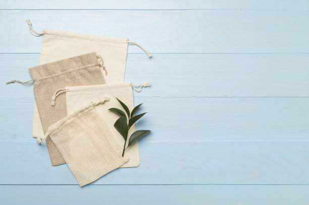 小生态袋与绿叶木制背景。俯视图图片下载