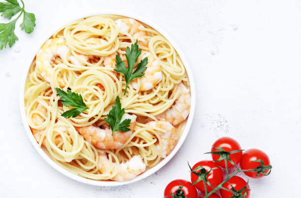 在盘子里准备虾面，西红柿和欧芹，白色的桌子背景。俯视图图片下载