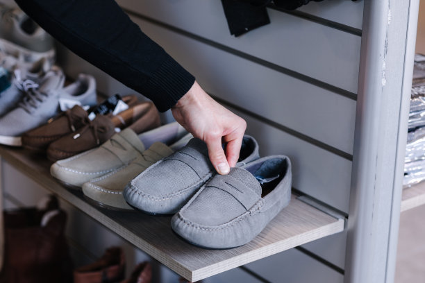 人们的手从服装店的货架上拿灰色的鹿皮鞋图片下载