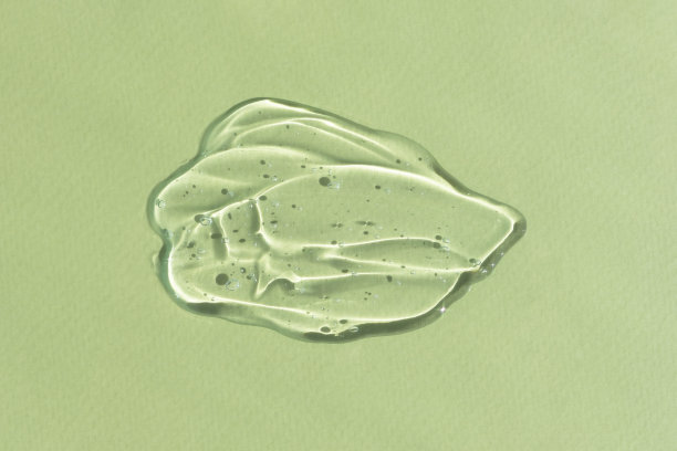 透明透明质凝胶或血清在绿色背景。涂抹护肤化妆品产品。健康和美丽的概念。俯视图图片下载